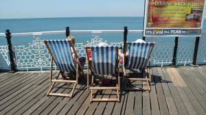Three people relaxing in deckchairs at the seaside. Photo by Becks Hobbs Photography
